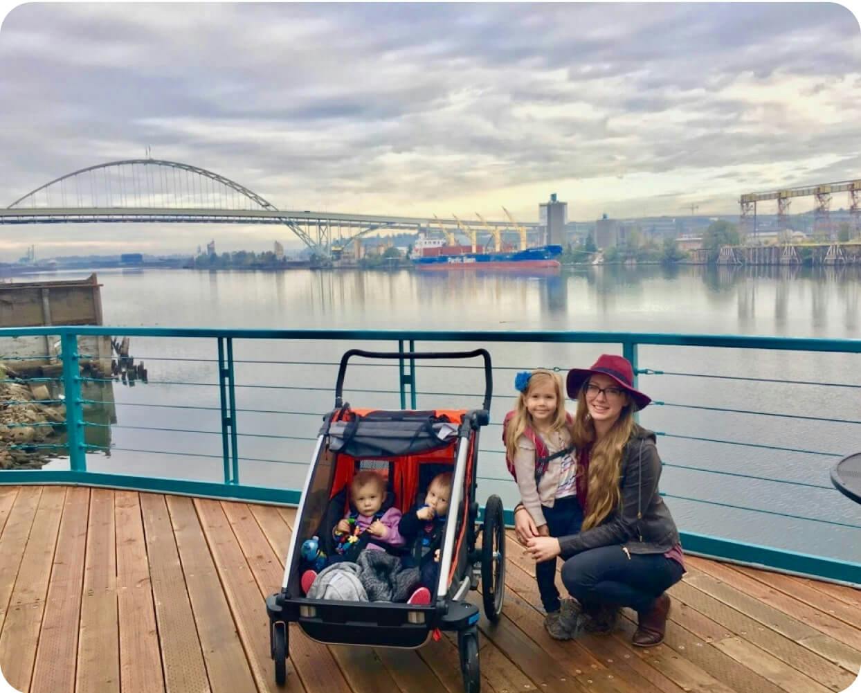 A photo of a mom with three kids, taken in front of an urban riverfront.